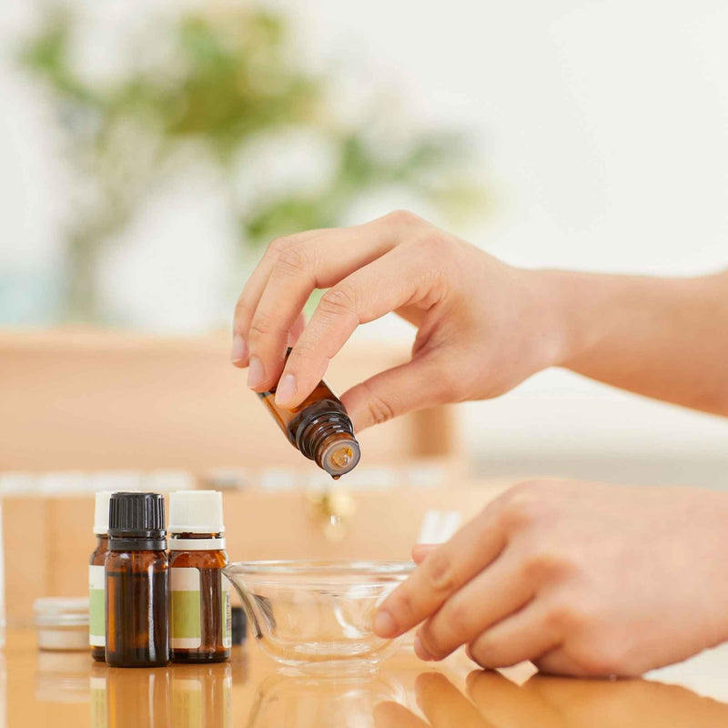 Flacons d’huiles essentielles naturels posés sur une table en bois, entourés de plantes fraîches et d’accessoires d’aromathérapie – un rappel visuel de l’importance d’utiliser les huiles essentielles avec précaution, comme le préconise Plantes & Recettes.