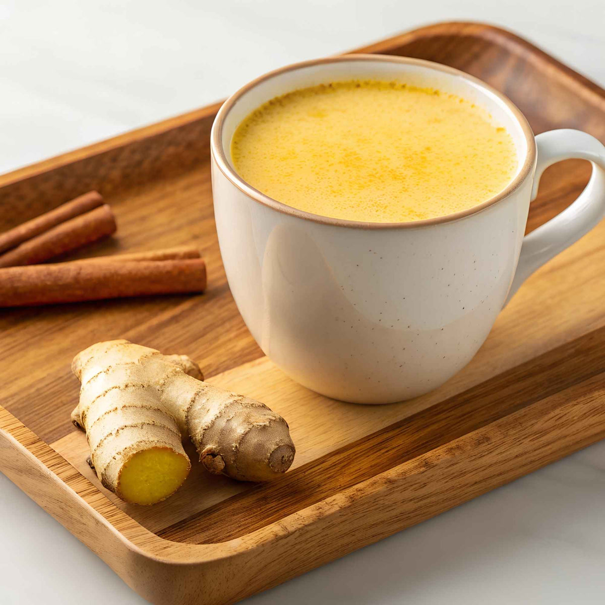 Tasse de Golden Latte chaud avec mousse onctueuse, curcuma et épices en arrière-plan, illustrant une recette bien-être naturelle et traditionnelle.