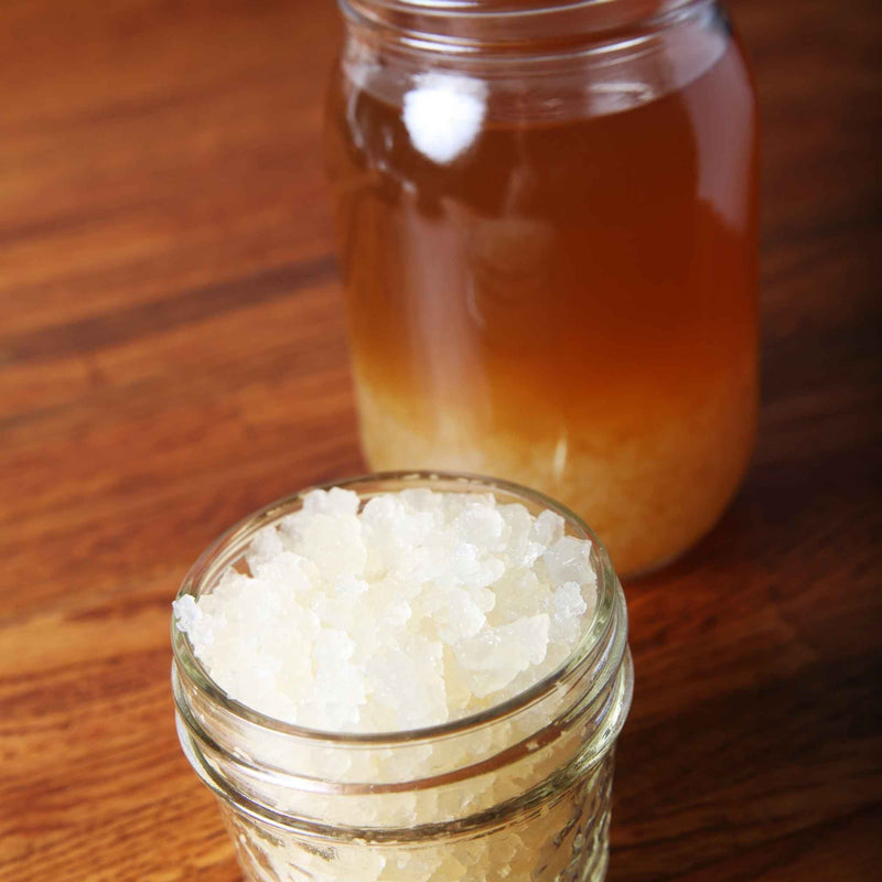 Un bocal de kéfir de fruits en fermentation avec figue et citron, prêt à devenir pétillant après la seconde fermentation