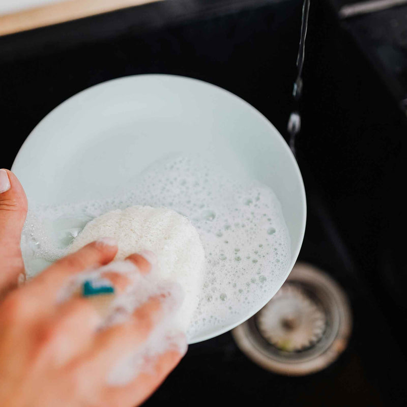 Photo d’un savon vaisselle solide fait maison dans un pot en verre, avec une éponge à côté