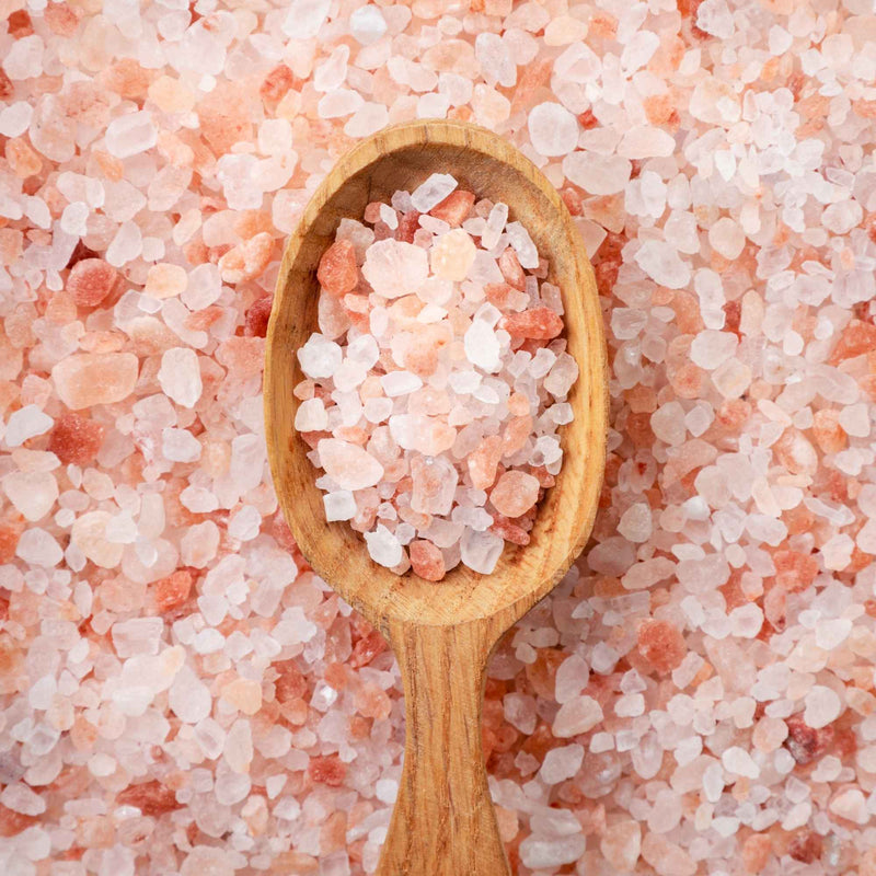 Gros sel rose de l’Himalaya dans une cuillère en bois, vu de près.
