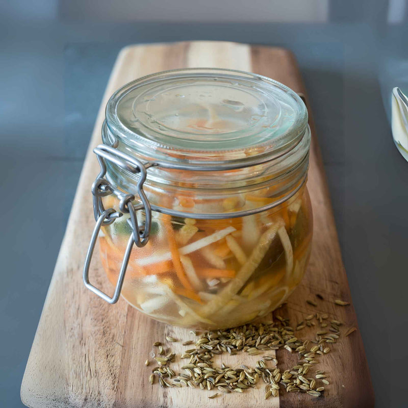 Bocal de légumes lactofermentés sur une planche en bois avec graines de fenouil.