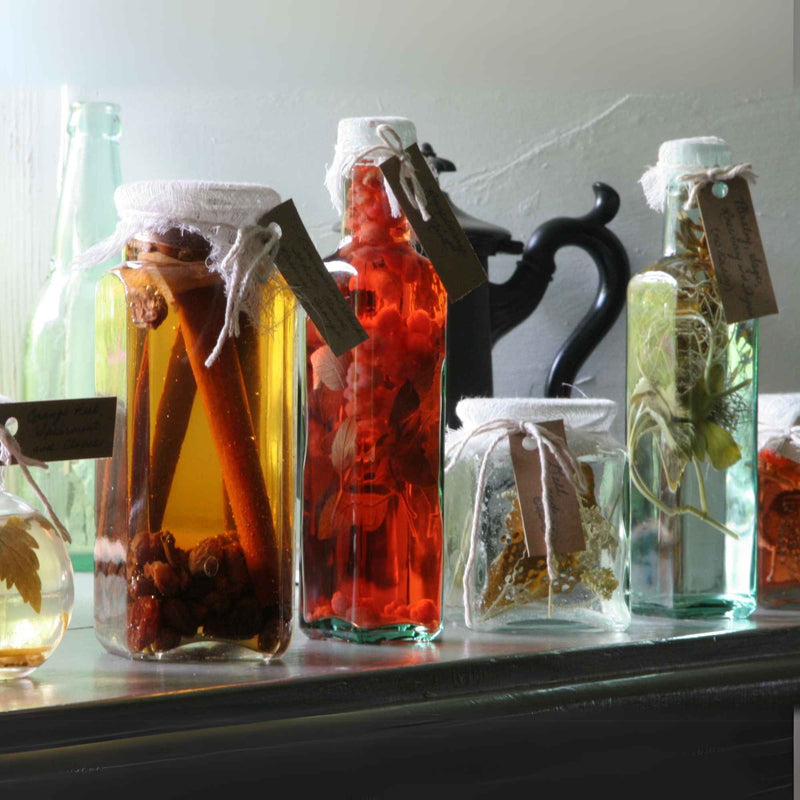 Bouteilles de vinaigre infusé aux épices et plantes sur une étagère de cuisine.