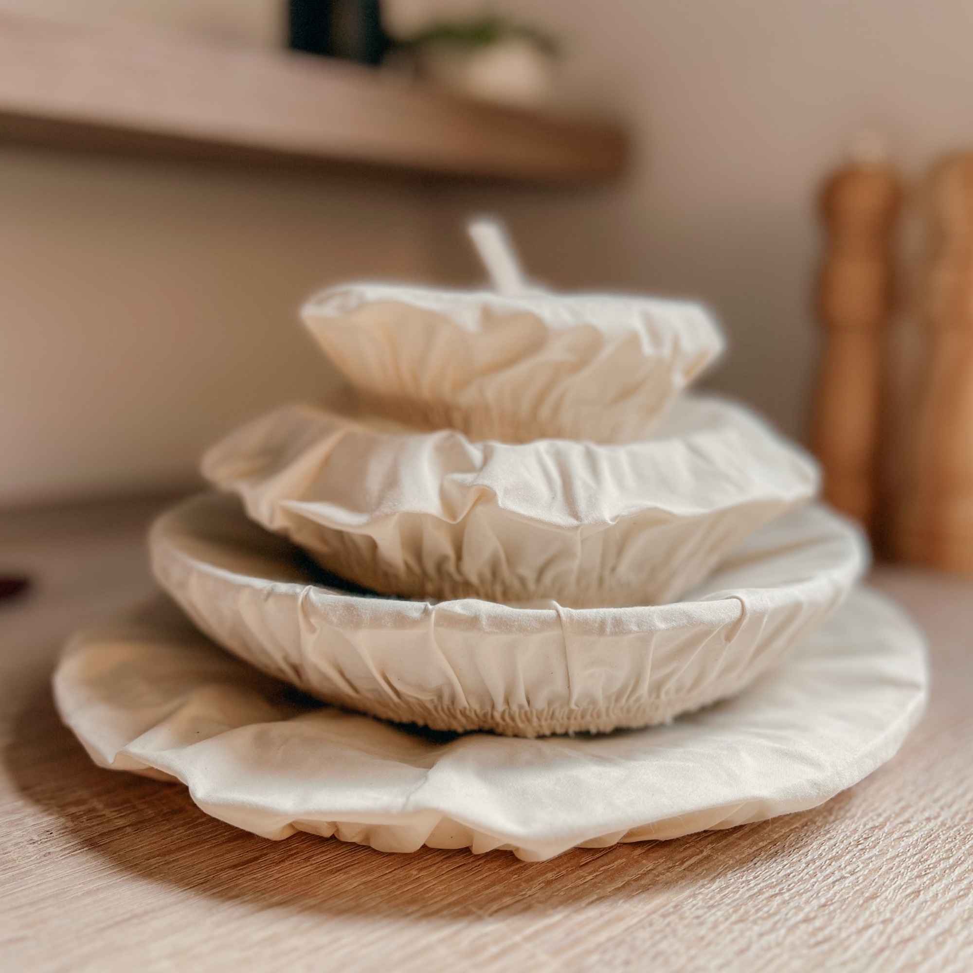 Ensemble de couvercles en coton bio réutilisables, empilés du plus grand au plus petit, une solution durable et écologique.