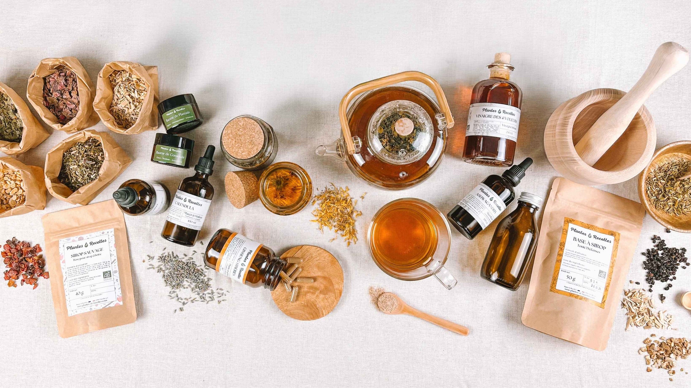 Ensemble de produits d'herboristerie artisanale comprenant des plantes médicinales séchées, tisanes, épices et ingrédients naturels préparés dans notre atelier