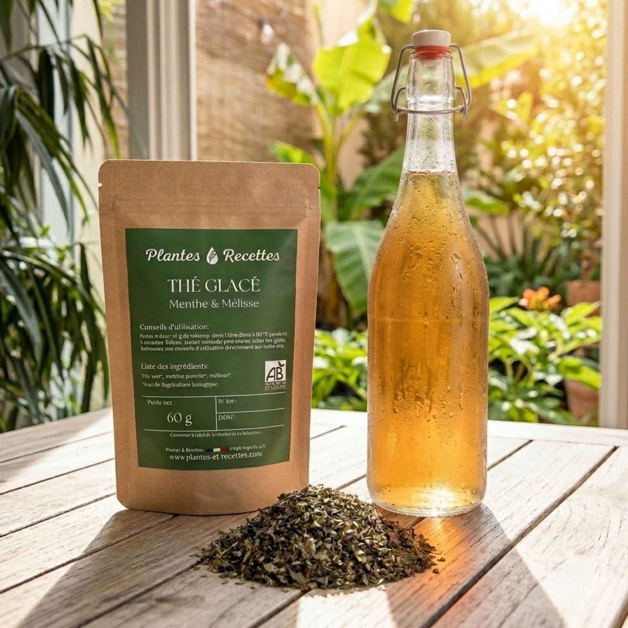 Sachet de thé glacé Menthe & Mélisse Plantes & Recettes accompagné d'une bouteille de thé glacé maison et d'un mélange de plantes biologiques.