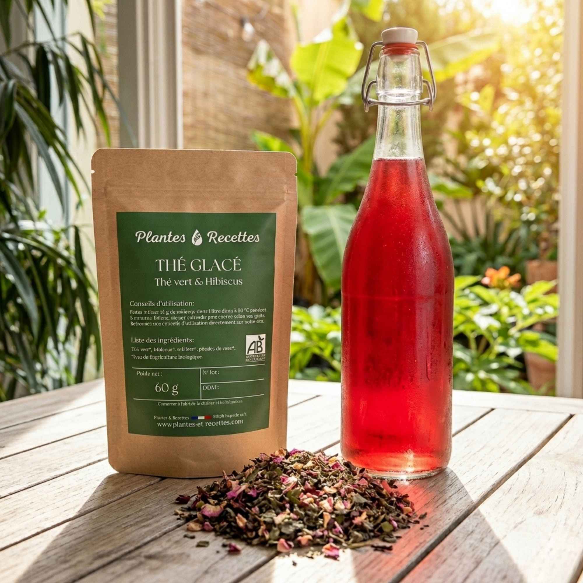 Sachet de thé glacé Thé vert & Hibiscus Plantes & Recettes avec bouteille de thé glacé maison et mélange de plantes biologiques sur une table en bois.
