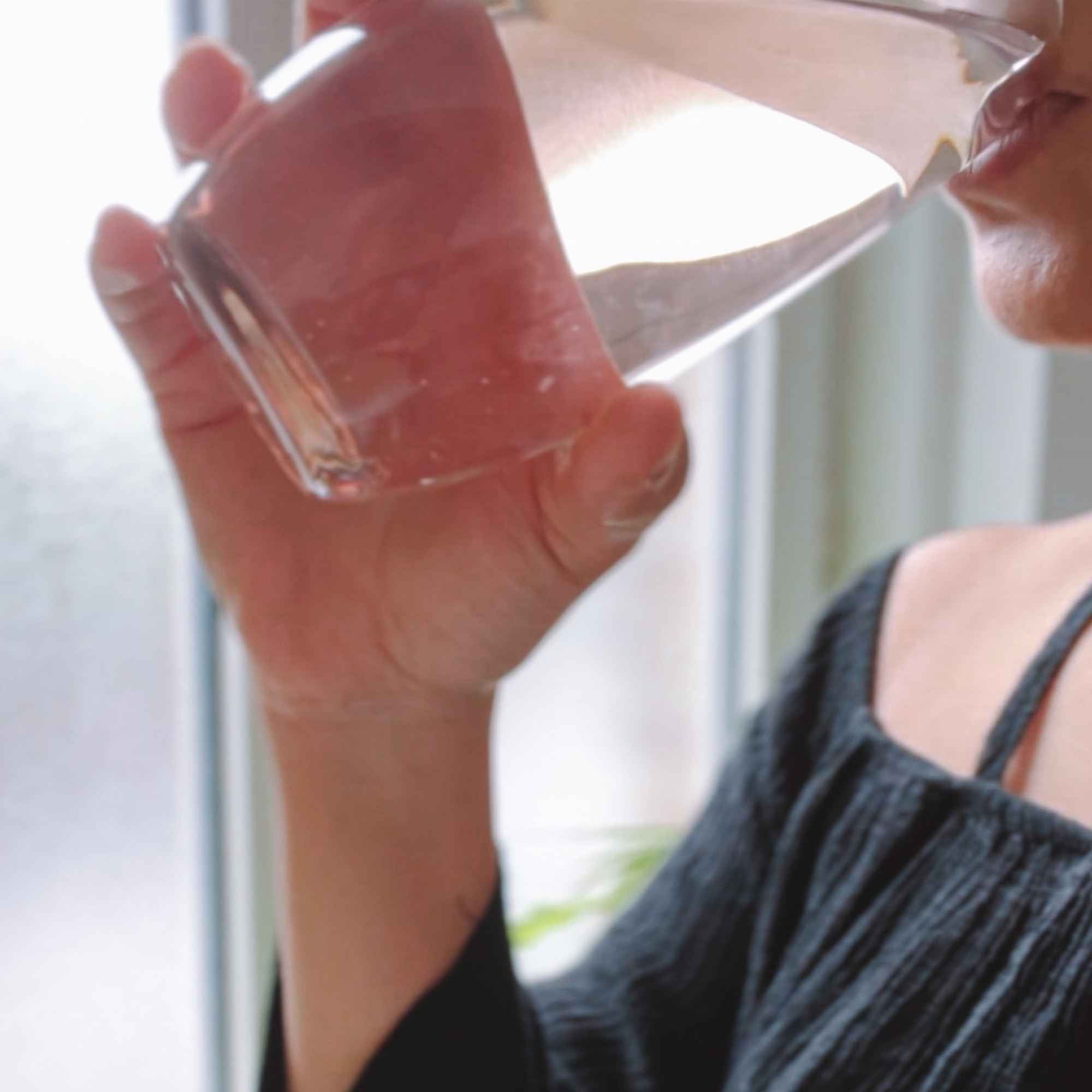 Consommation d’un verre d’eau contenant une teinture de plante bio – extrait naturel préparé par Plantes & Recettes en herboristerie.