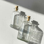 Bouteilles apothicaires rondes en verre clair 250 ml et 500 ml avec bouchon en liège naturel.