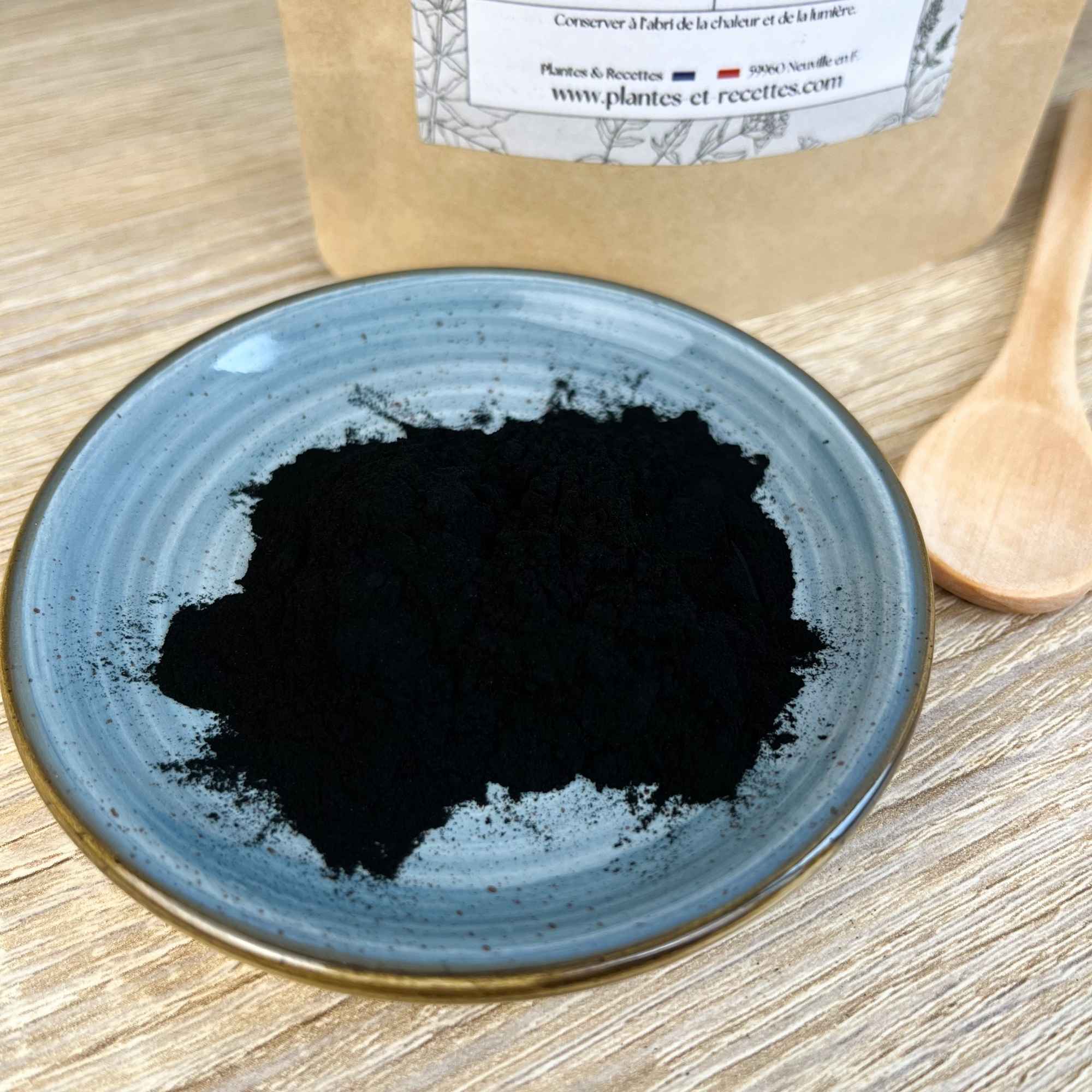 Charbon actif végétal en poudre présenté dans une coupelle, produit naturel Plantes & Recettes pour soins du visage et recettes purifiantes.