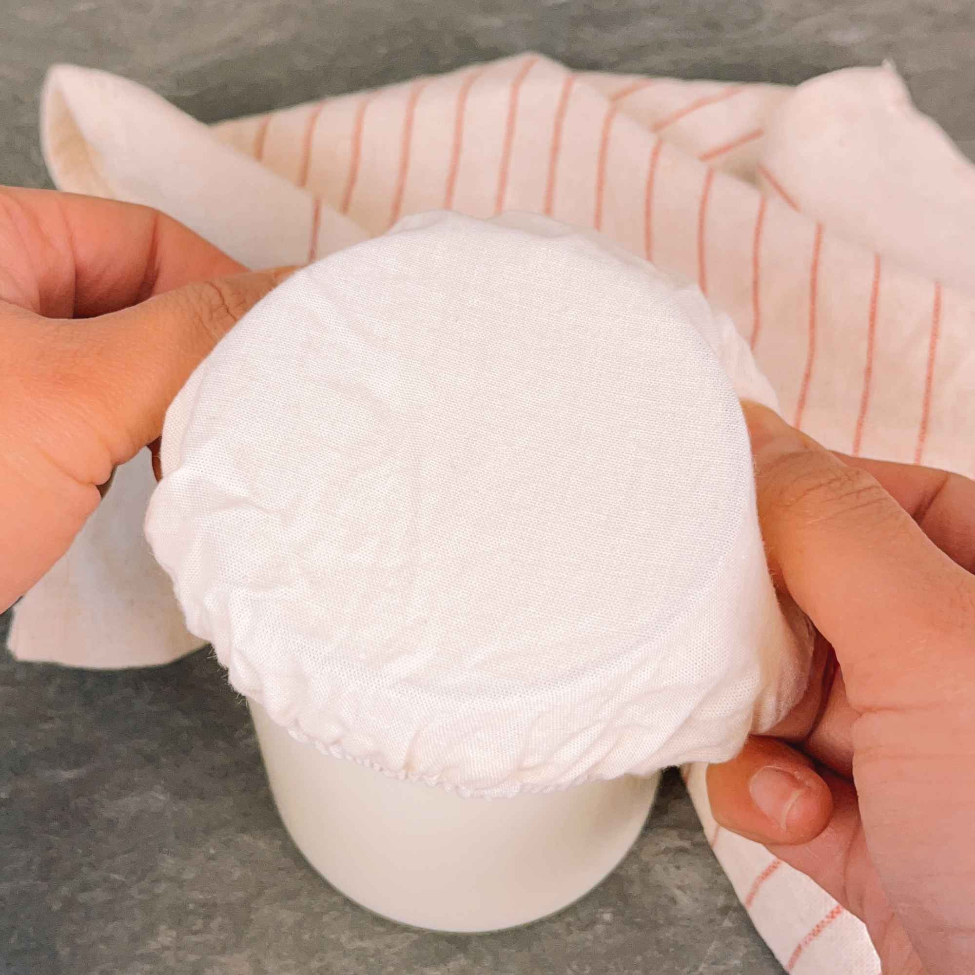 Couvre-pot en tissu coton avec élastique, posé sur un bocal pour fermentation de kéfir de lait maison.
