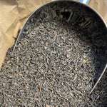 Feuilles de thé noir bio de Chine, séchées et entières, prêtes pour infusion, offrant une boisson tonique aux arômes riches et boisés.