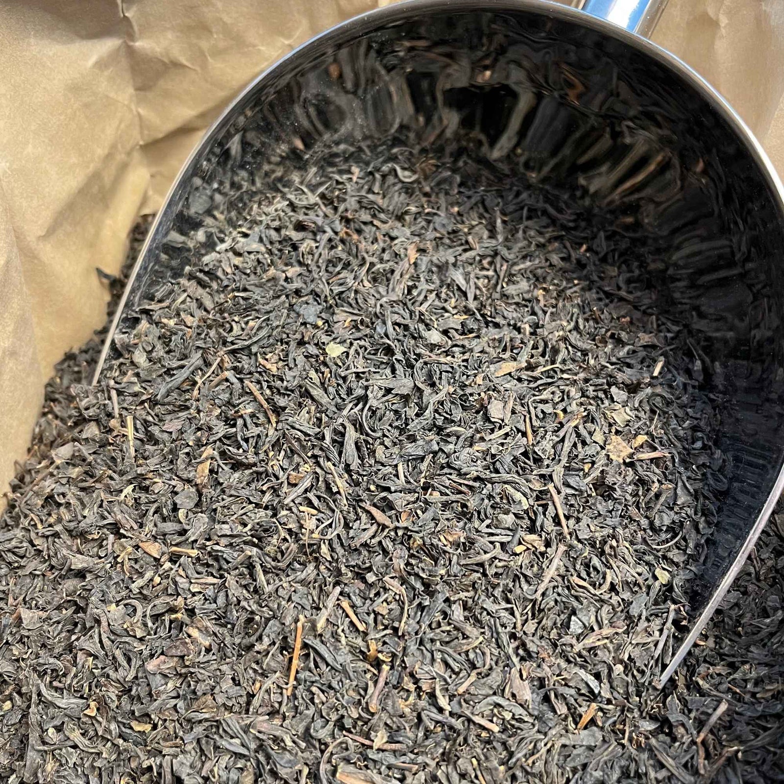 Feuilles de thé noir bio de Chine, séchées et entières, prêtes pour infusion, offrant une boisson tonique aux arômes riches et boisés.