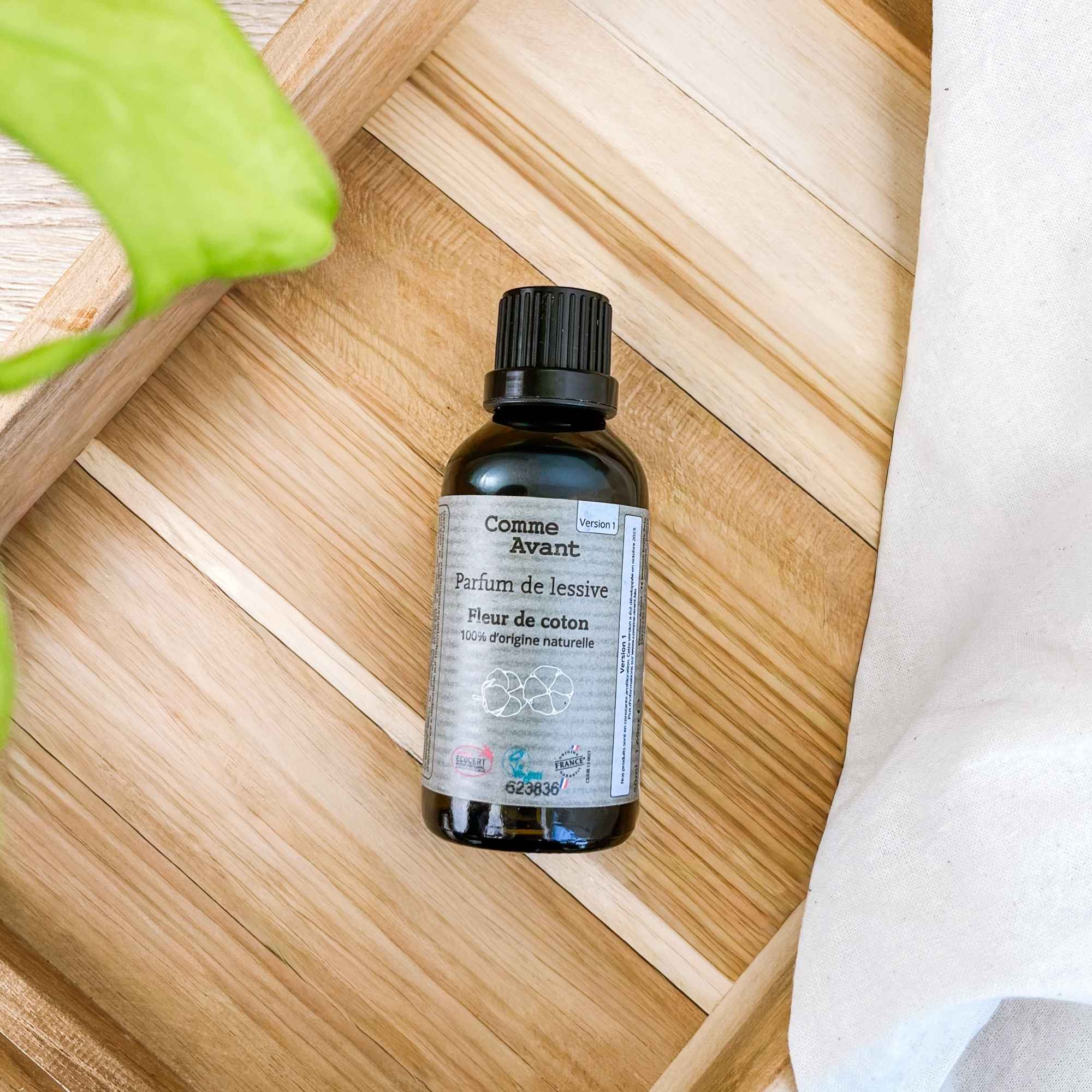 Flacon de parfum de lessive fleur de coton posé dans un décor naturel, idéal pour parfumer le linge au quotidien.