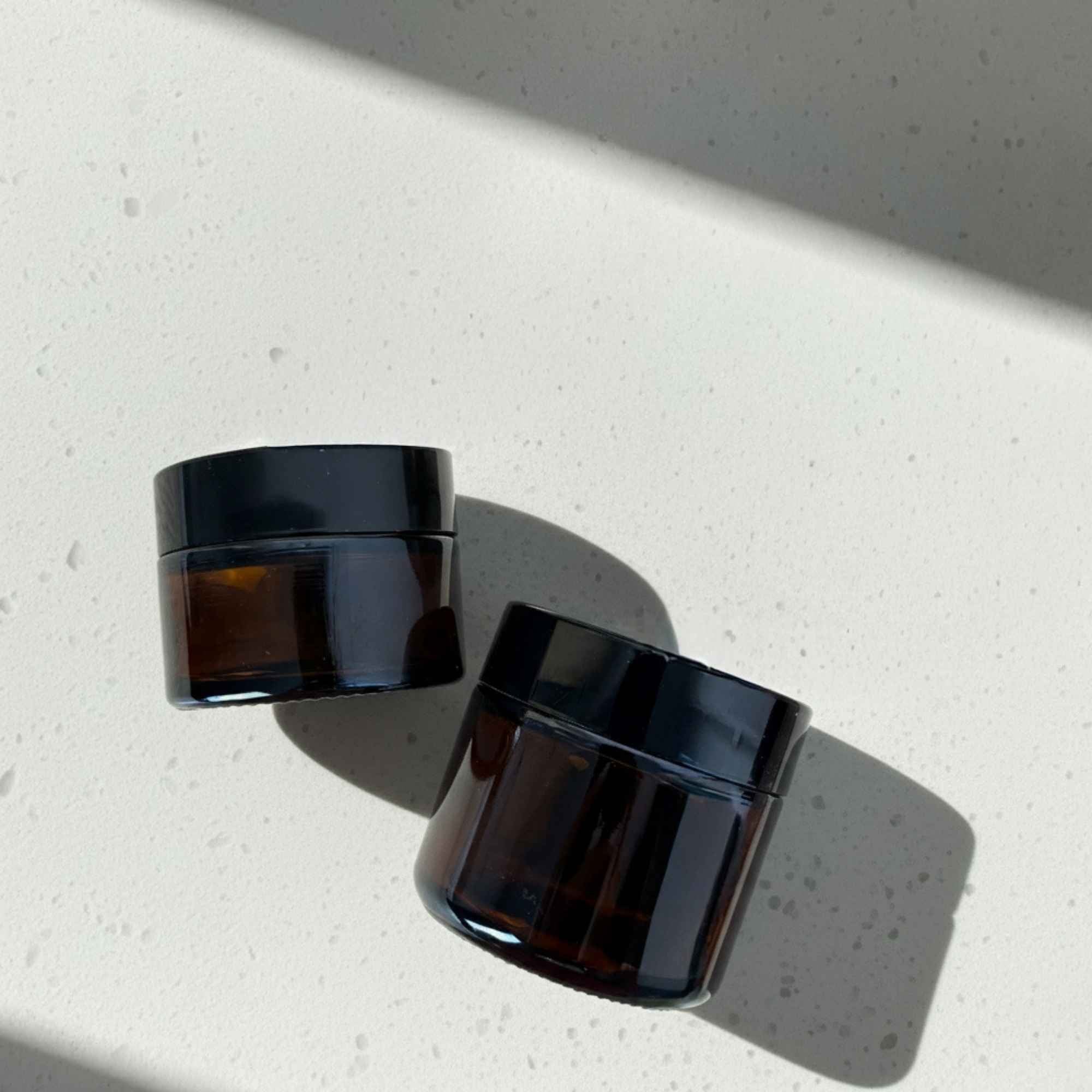 Pot à baume en verre ambré avec couvercle noir, idéal pour vos préparations maison.