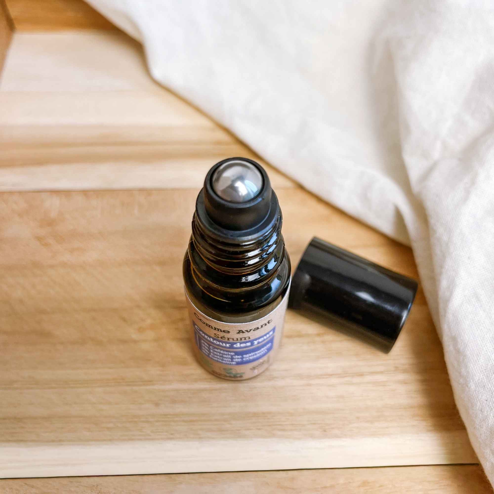 Flacon de sérum contour des yeux roll-on posé en mise en scène, idéal pour lisser et hydrater la zone du regard.