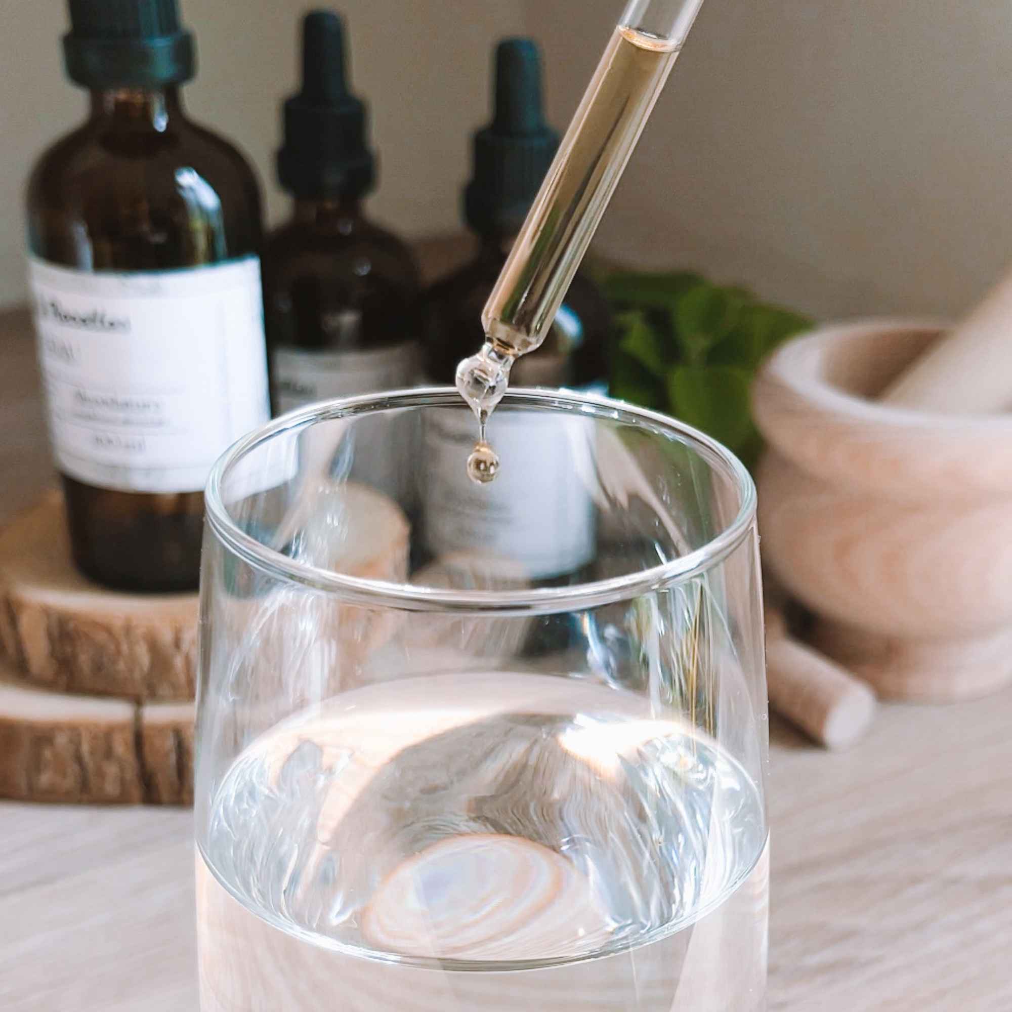 Gouttes de teinture de plante bio diluées dans un verre d’eau, préparation naturelle Plantes & Recettes – herboristerie artisanale.